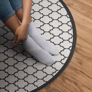 May include: A round area rug with a black and white geometric pattern. The rug has a black border and is made of a soft, durable material.