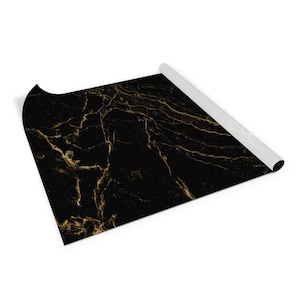 May include: A roll of black and gold marble patterned wrapping paper. The paper is rolled up and the end is visible.