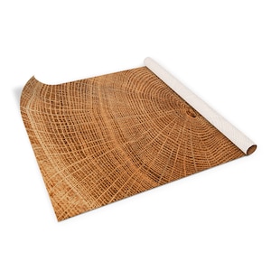 May include: A close-up of a wood grain pattern, showing the rings of a tree trunk. The wood is a light brown color with darker brown lines.