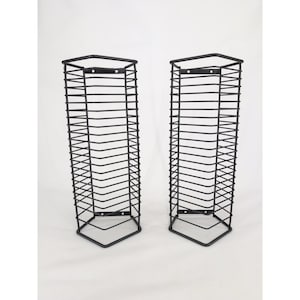 May include: Two tall, rectangular wall-mounted storage racks constructed from thin black metal wire. Each unit features a series of horizontal rungs forming a grid-like structure with mounting brackets at the top and bottom for secure attachment.