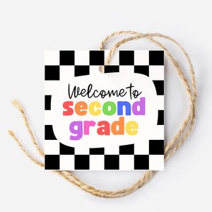 Może przedstawiać: Kwadratowa etykieta z czarno-białą szachownicą i napisem "Welcome to second grade" w kolorowych literach. Etykieta jest związana naturalnym sznurkiem.