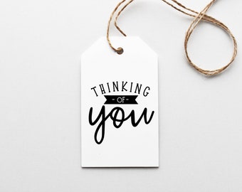 Pode incluir: Etiqueta de presente branca com texto preto que diz "Thinking -of- you".