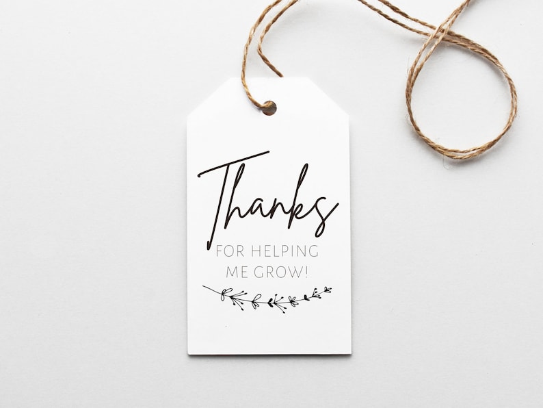 K&ouml;nnte beinhalten: Wei&szlig;er Geschenkanh&auml;nger mit schwarzem Text, der "Danke, dass du mir beim Wachsen hilfst!" lautet, mit einem kleinen schwarzen Blumenmuster am unteren Rand.