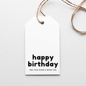 Peut inclure: Étiquette cadeau blanche avec du texte noir qui dit "joyeux anniversaire" et "un an de plus et plus sage aussi".