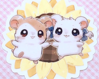 Puede incluir: Dos hámsters de dibujos animados, uno marrón y otro blanco, están sentados dentro de un girasol amarillo. Los hámsters sonríen y se toman de la mano. El girasol tiene un centro marrón y pétalos amarillos.