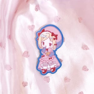 May include: A sticker featuring a cartoon girl with blonde hair wearing a pink dress and a blue hat. She is holding a small, yellow object in her hands. The sticker is on a pink background with small, white hearts.