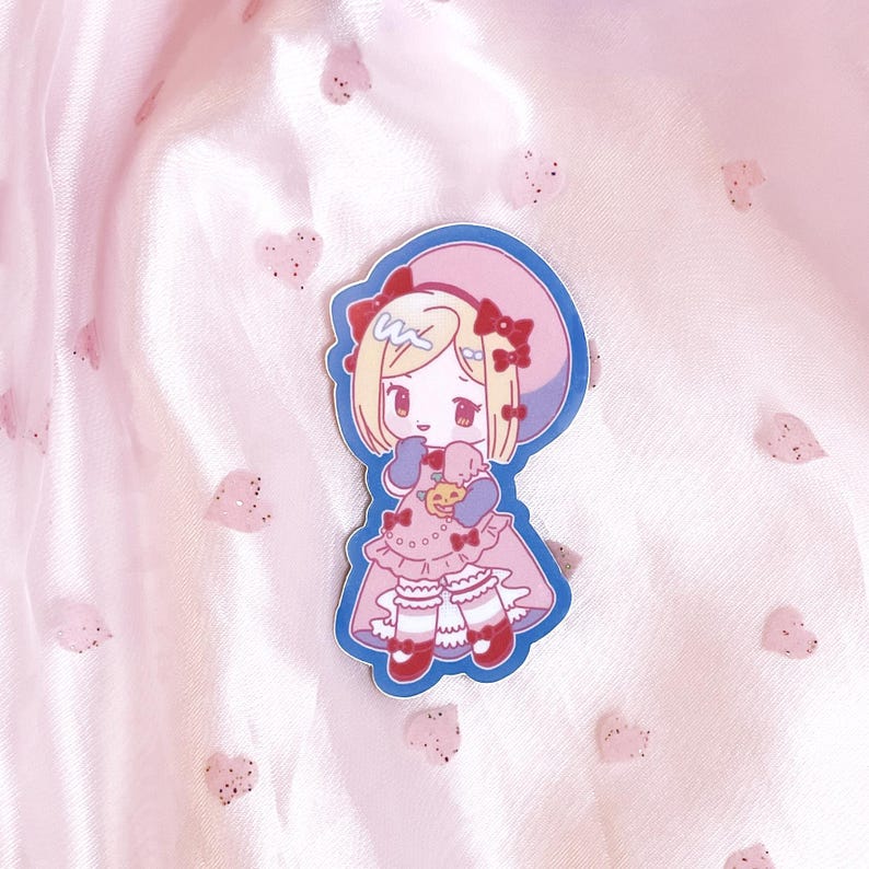 May include: A sticker featuring a cartoon girl with blonde hair wearing a pink dress and a blue hat. She is holding a small, yellow object in her hands. The sticker is on a pink background with small, white hearts.