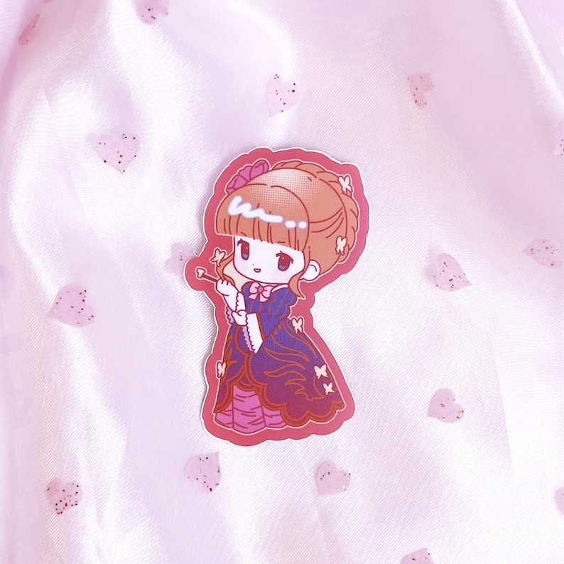 May include: A sticker featuring a cartoon girl with brown hair, wearing a purple and pink dress with butterfly accents. The sticker has a pink background.