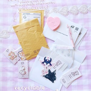 various items related to recycling and reusing, including a recycled mail envelope, a pink heart-shaped sticker, a pen, and some other miscellaneous items.