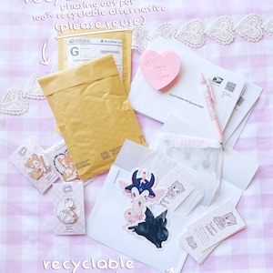 various items related to recycling and reusing, including a recycled mail envelope, a pink heart-shaped sticker, a pen, and some other miscellaneous items.