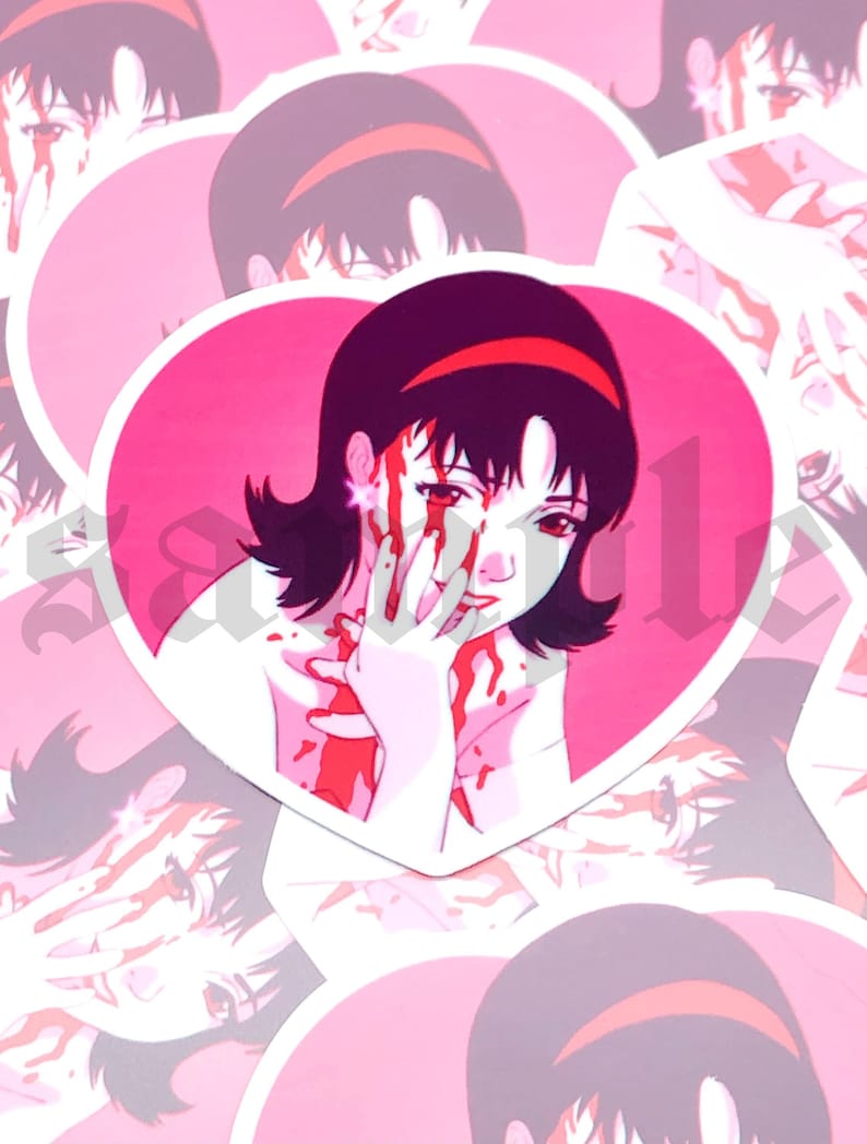 Op de afbeelding: Een roze sticker in de vorm van een hart met een cartoonafbeelding van een vrouw met zwart haar en een rood hoofdband. De vrouw heeft bloed op haar gezicht en handen.