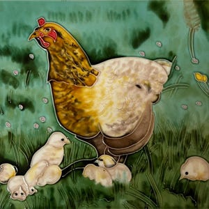 May include: A decorative ceramic tile featuring a hand-painted illustration of a golden-brown hen standing in a green grassy field. The hen is surrounded by several small, light-colored chicks scattered throughout the grass, with a soft teal background.