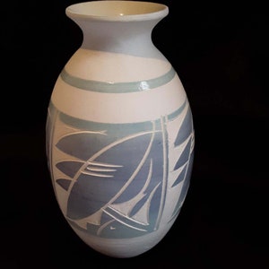 May include: White ceramic vase with a blue and white leaf design. The vase has a rounded body and a narrow neck.