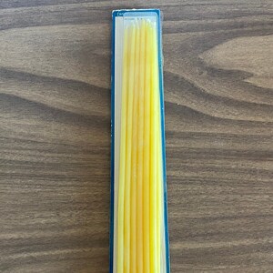 May include: A package of 12 yellow beeswax candles in a clear plastic box with a blue border.