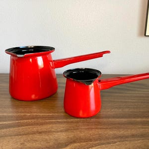 pair of red enamelware pots with pour spouts