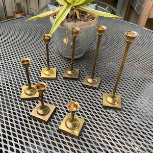 7 graduated brass candlestick holders | square base