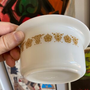 May include: White ceramic bowl with a gold floral pattern around the rim. The bowl is slightly angled and the rim is slightly raised.