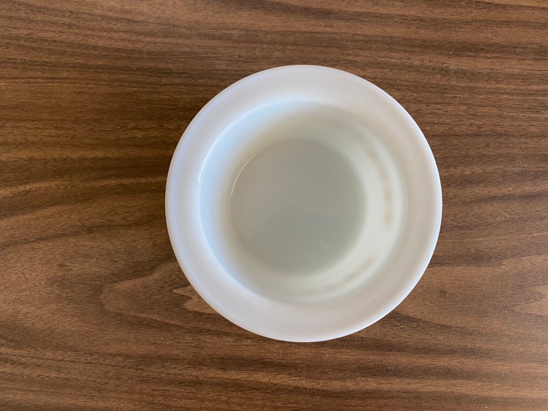 May include: A white ceramic bowl with a smooth, rounded rim. The bowl is empty and has a slight sheen.