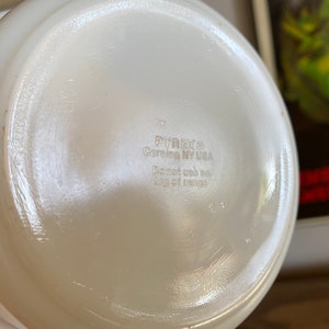 May include: White Pyrex glass bowl with a smooth, white interior. The bottom of the bowl has the text "Pyrex Corning NY USA" and "Do not use on top of range".