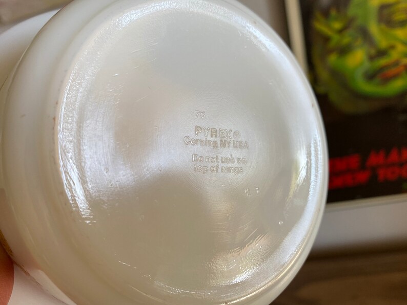 May include: White Pyrex glass bowl with a smooth, white interior. The bottom of the bowl has the text "Pyrex Corning NY USA" and "Do not use on top of range".