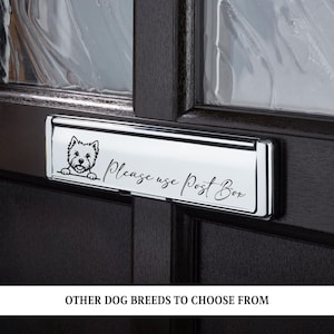 May include: A rectangular chrome letter plate for a door featuring a black graphic of a West Highland White Terrier and the black script text Please use Post Box. The metal plate has a reflective finish and is mounted on a dark brown door.