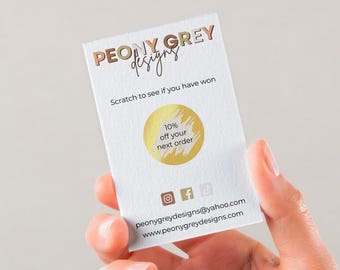 May include: A white card with gold lettering that reads "PEONY GREY designs". The card has a gold scratch-off circle that says "10% off your next order". The card also includes social media icons and contact information for the business.
