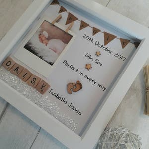 Pode incluir: Moldura branca com uma foto de beb&ecirc;, uma faixa que diz "Baby Girl", e o texto "20th October 2017", "8lbs 5oz", "Perfect in every way", "Daisy", e "Isabella Jones".