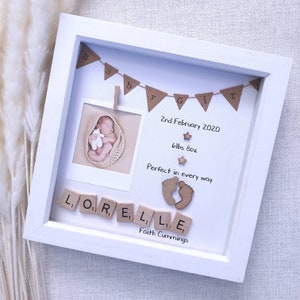 Pode incluir: Moldura branca com uma foto de beb&ecirc;, uma faixa que diz "Baby Girl" e o nome do beb&ecirc; escrito com pe&ccedil;as de letras de madeira. A data "2nd February 2020", o peso "6lbs 8oz" e a frase "Perfect in every way" est&atilde;o escritas na moldura. O nome "Faith Cummings" est&aacute; escrito na parte inferior da moldura.