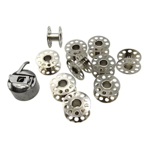 May include: A set of 9 silver metal bobbins for a sewing machine. The bobbins are round with a hole in the center and a series of small holes around the edge. There is also a silver metal bobbin winder.