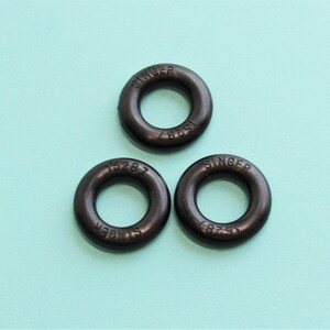 May include: Three black rubber rings with the word "SINGER" and numbers printed on them.