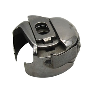 May include: A silver sewing machine bobbin case with a metal hook and a spring-loaded latch.