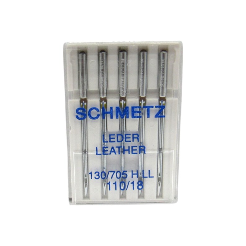 May include: A pack of five silver sewing needles in a clear plastic case. The needles are labeled "Schmetz Leder Leather 130/705 HLL 110/18".