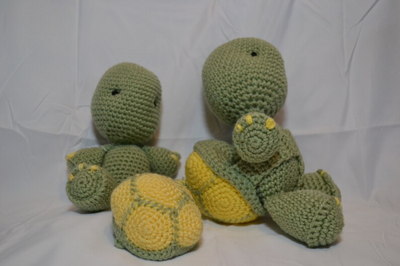 Pu&ograve; includere: Due peluche di tartaruga verde all'uncinetto con accenti gialli. Una tartaruga &egrave; seduta con le braccia incrociate, mentre l'altra &egrave; sdraiata con le gambe distese.