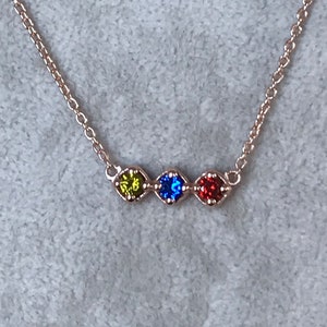 Puede incluir: Un delicado collar de cadena de plata con cuatro peque&ntilde;os acentos de piedras preciosas. Las piedras preciosas son verdes, azules, rojas y transparentes.