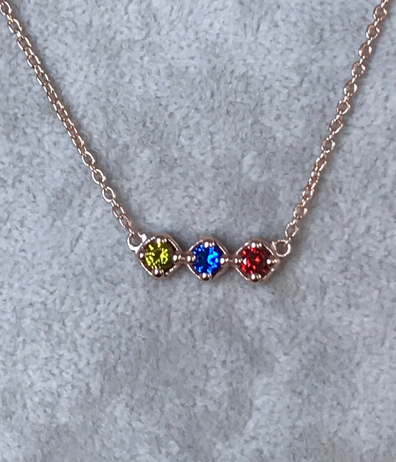 Puede incluir: Un delicado collar de cadena de plata con cuatro peque&ntilde;os acentos de piedras preciosas. Las piedras preciosas son verdes, azules, rojas y transparentes.