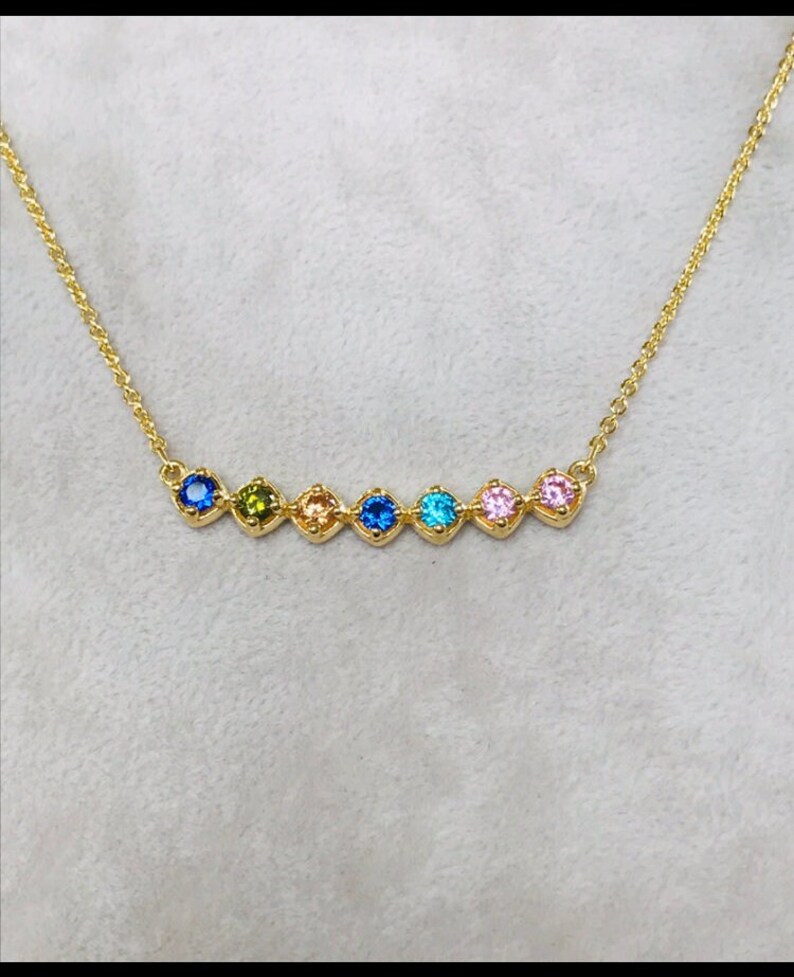 Puede incluir: Un collar de cadena de oro con una fila de siete piedras preciosas de colores. Las piedras preciosas est&aacute;n engastadas en oro y est&aacute;n dispuestas en un patr&oacute;n de arco&iacute;ris.