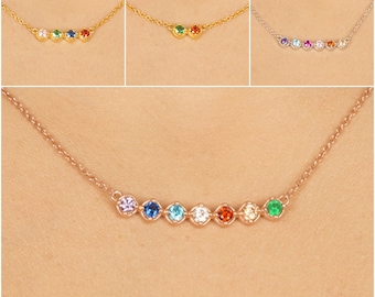 Puede incluir: Un delicado collar de cadena de oro con una fila de piedras preciosas de colores. Las piedras están dispuestas en forma de arcoíris, comenzando por el morado y terminando por el verde.