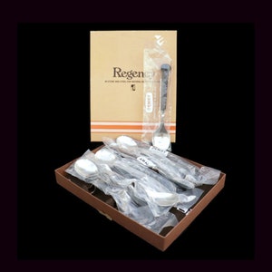 May include: A set of six silver spoons with black handles in a brown box. The box has the text "Regency in stone and steel for natural beauty" and "Denby" printed on it.