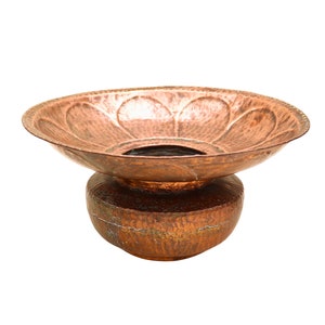 May include: A hammered copper planter with a wide, shallow bowl and a round base. The planter has a rustic, aged look.