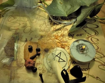 May include: A white candle with a silver top sits on a parchment paper background with a small bag of herbs, a black stone, a rolled up scroll tied with a black ribbon, and a pentagram symbol.