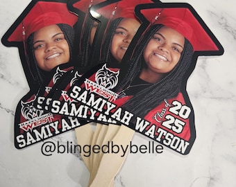 May include: A set of graduation fan cutouts with a black and red color scheme. The fans feature a photo of a graduate wearing a red cap and gown, the text "Samiyah Watson", "Hazelwood West", "Class of 2025", and the social media handle "@blingedbybelle".
