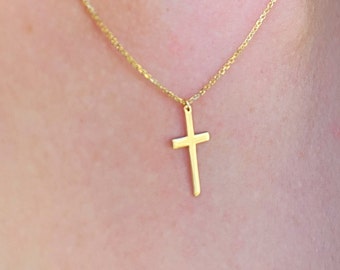 May include: A gold chain necklace with a small, simple gold cross pendant.