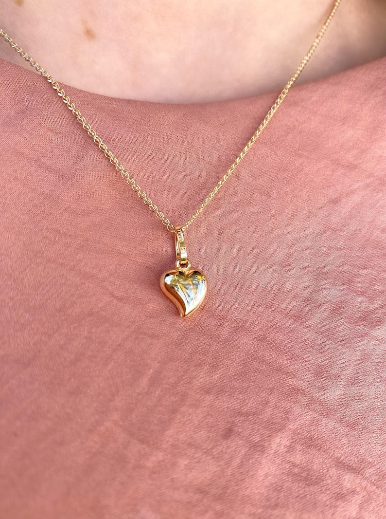 May include: A gold chain necklace with a small, heart-shaped pendant.