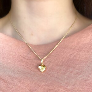 May include: A gold chain necklace with a small, heart-shaped pendant.