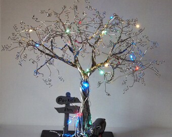 May include: A silver wire tree sculpture with colorful lights and a sign that reads "Porkie's Pen". A small pig figurine is at the base of the tree.