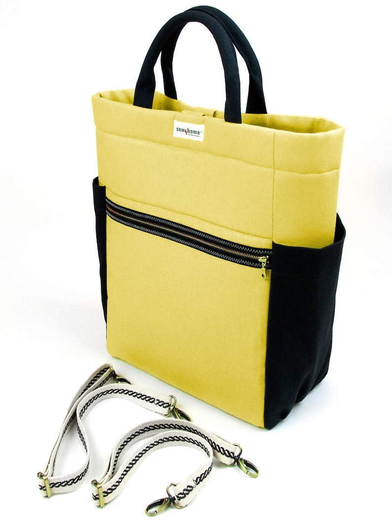 May include: A yellow tote bag with black trim and a black zippered pocket. The bag has a black handle and a detachable shoulder strap with a white and black braided design.