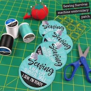 May include: Five turquoise blue round embroidered patches with the text "Sewing A Real Life Survival Skill I Sew. I'm Ready" on a green cutting mat with spools of white, black, and turquoise thread and a pair of blue scissors.