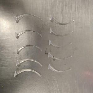 Ten curved clear plastic flight stands arranged in two vertical columns on a metallic surface.