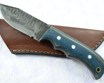 May include: A blue and white handled knife with a leather sheath. The blade has a hammered finish.