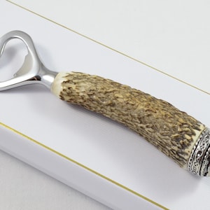 May include: A silver bottle opener with a brown antler handle and a silver decorative end cap.